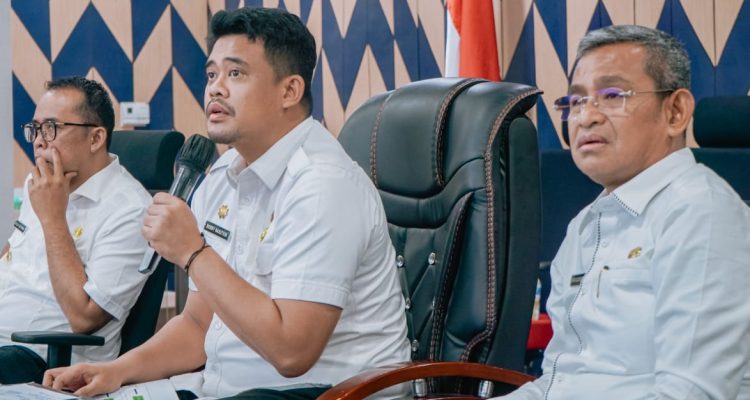 Teks: Wali Kota Medan Bobby Nasution saat didampingi Wakil Wali Kota Aulia Rahman dan Sekda Kota Medan Wiriya Alrahman memimpin rapat konsolidasi dan percepatan pembahasan pelaksanaan agenda pembangunan Kota Medan secara dini dan terarah melalui zoom meeting di Command Center, Balai Kota Medan meminta Bappeda dan OPD untuk berkolaborasi turun bersama mengutip pajak guna peningkatan PAD Kota Medan.(Dok:informasiterpercaya.com)