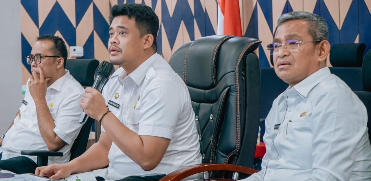 Teks: Wali Kota Medan Bobby Nasution saat didampingi Wakil Wali Kota Aulia Rahman dan Sekda Kota Medan Wiriya Alrahman memimpin rapat konsolidasi dan percepatan pembahasan pelaksanaan agenda pembangunan Kota Medan secara dini dan terarah melalui zoom meeting di Command Center, Balai Kota Medan meminta Bappeda dan OPD untuk berkolaborasi turun bersama mengutip pajak guna peningkatan PAD Kota Medan.(Dok:informasiterpercaya.com)